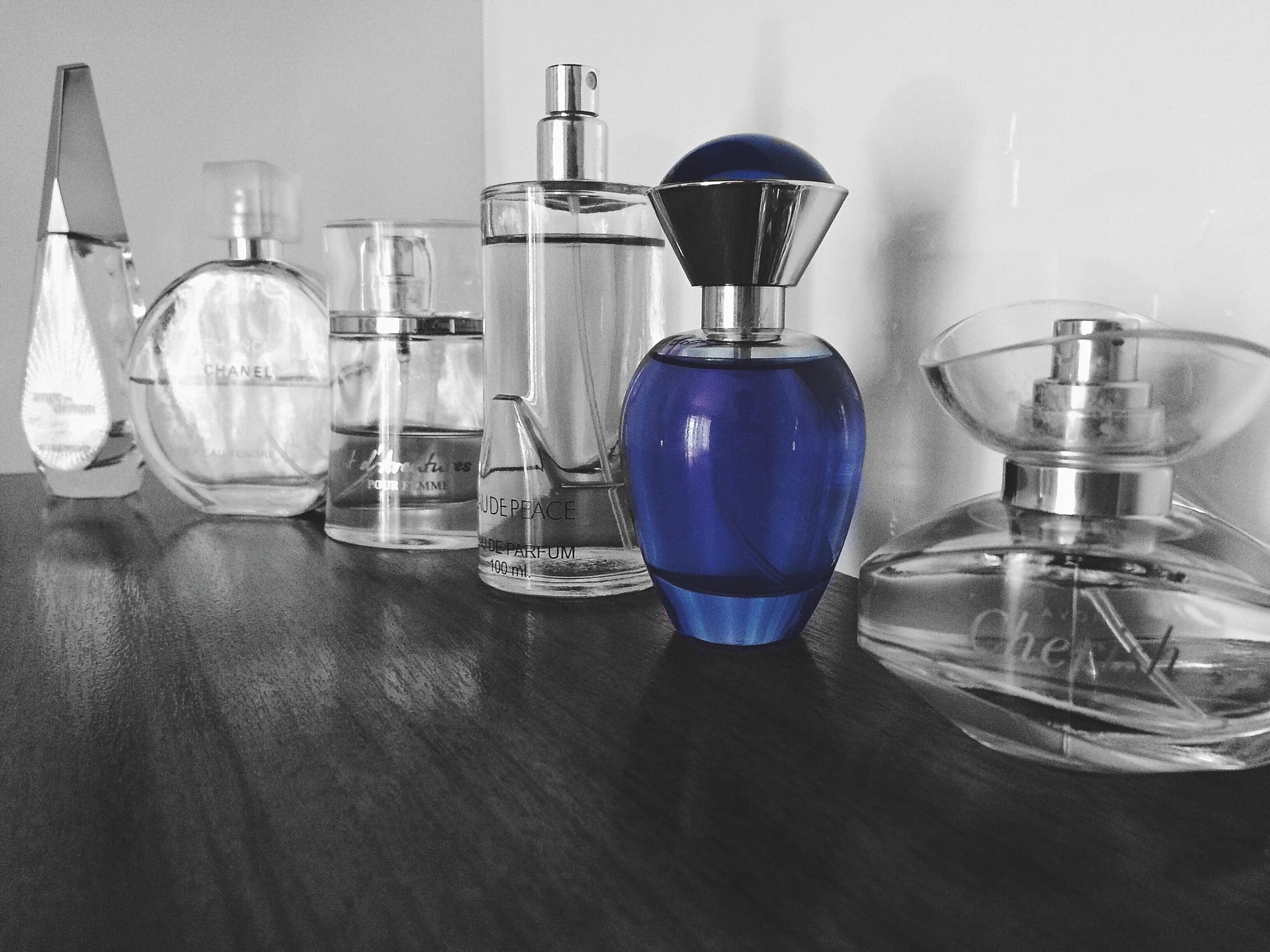 Cologne bottles arranged with bergamot and birch on a warm wooden surface in soft natural light