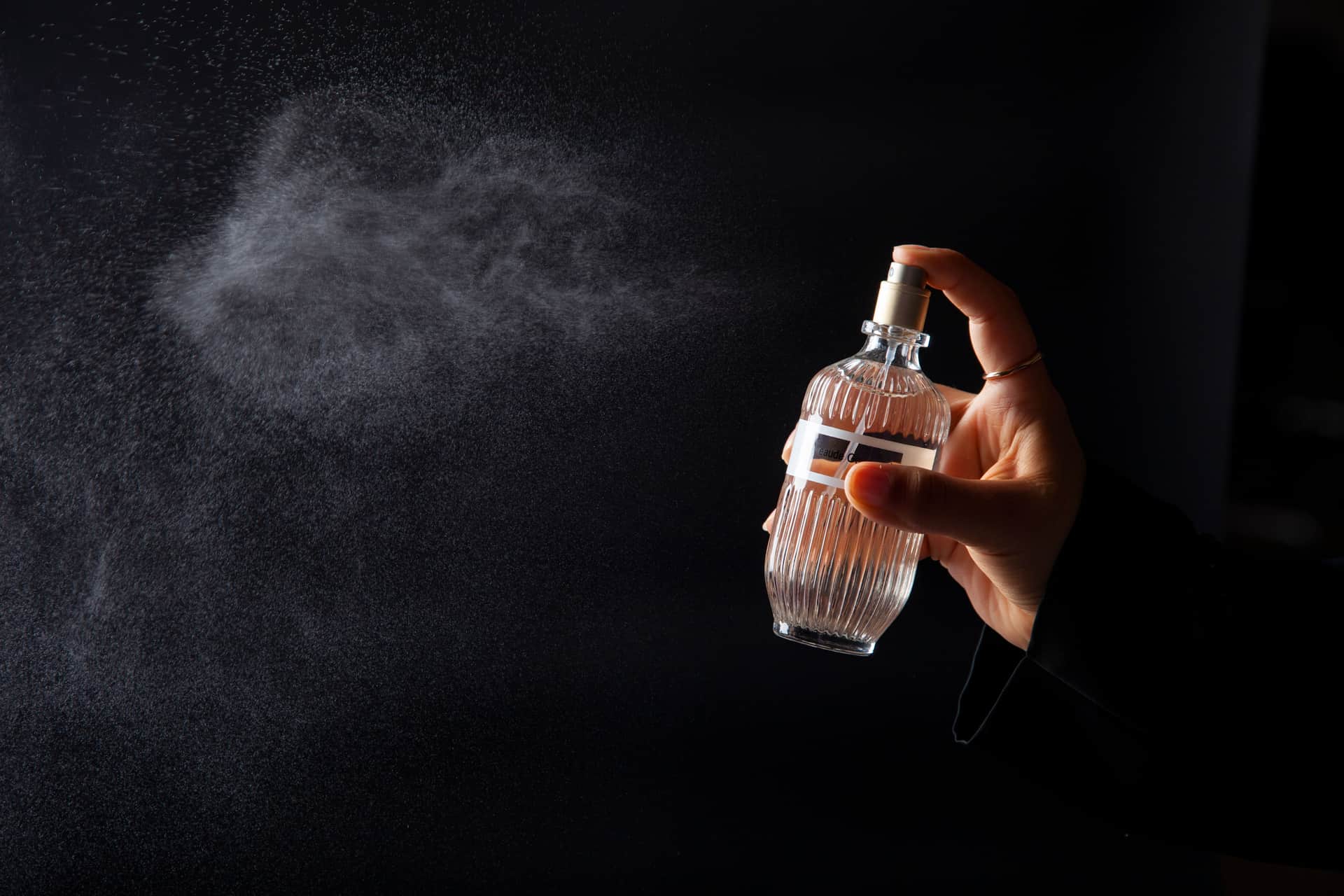 A fragrance bottle and a bare wrist in soft daylight