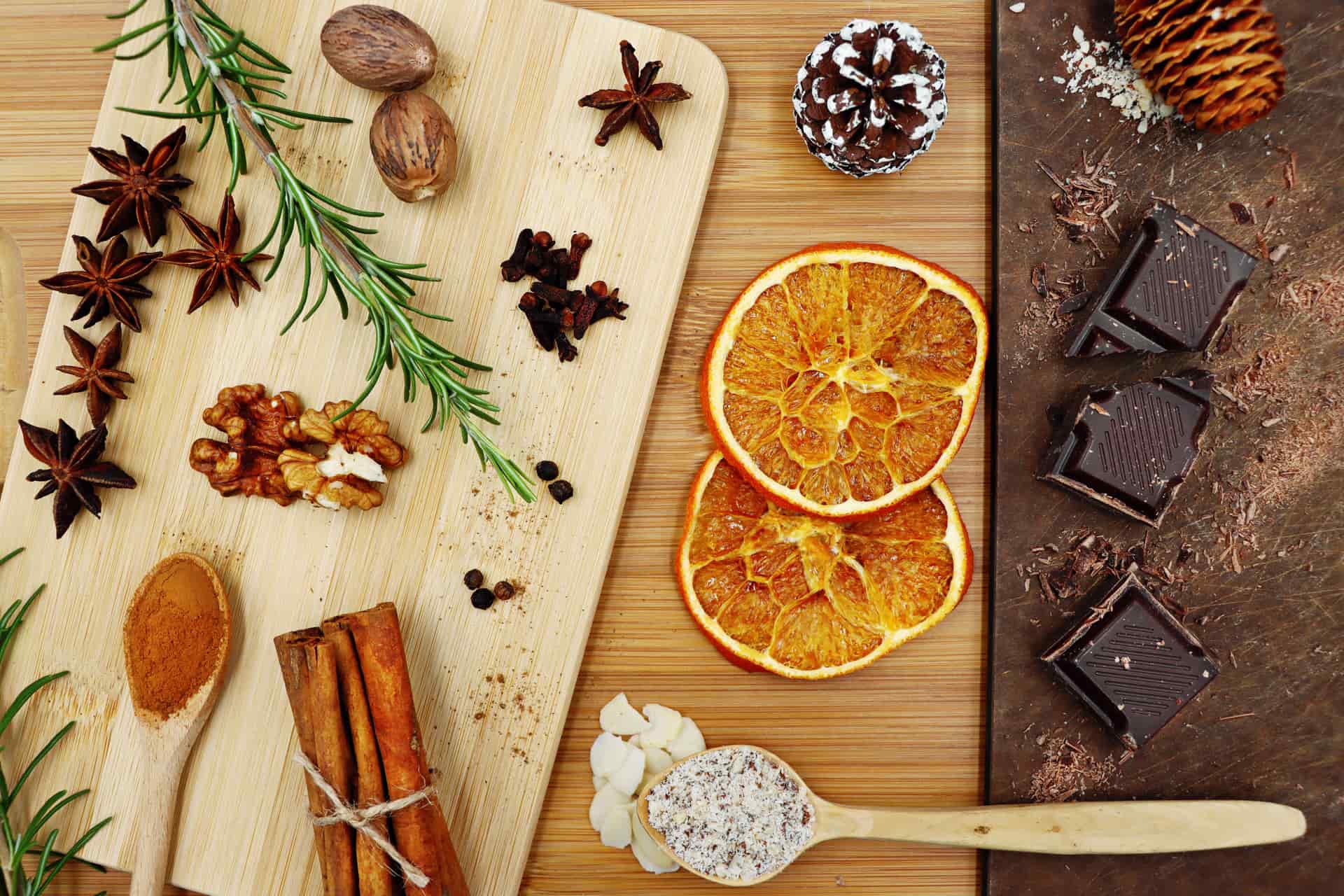A flat-lay of fragrance ingredients — citrus, spices and wood — on paper